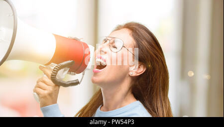 Medioevo donna che indossa un maglione di lana e raffreddare i bicchieri comunica gridando forte tenendo un megafono, esprimendo il successo e la concezione positiva, idea f Foto Stock