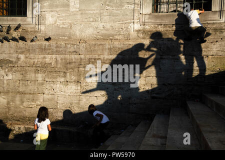 Istanbul, Turchia - 8 Settembre 2010: due bambina sono state giocando con i piccioni. Un ragazzo stava salendo alla parete. Le ombre degli adulti Nizza. Foto Stock