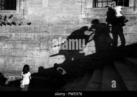 Istanbul, Turchia - 8 Settembre 2010: due bambina sono state giocando con i piccioni. Un ragazzo stava salendo alla parete. Le ombre degli adulti Nizza. Foto Stock