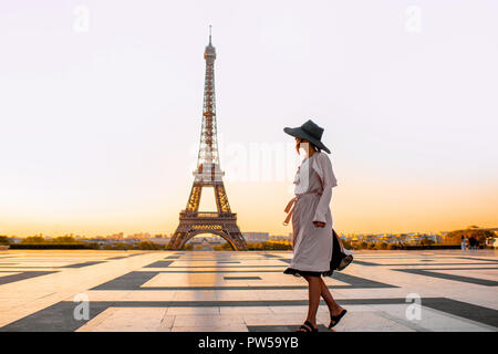 Donna vestita di cappotto e hat camminando sulla famosa piazza con vista sulla Torre Eiffel al mattino presto a Parigi Foto Stock