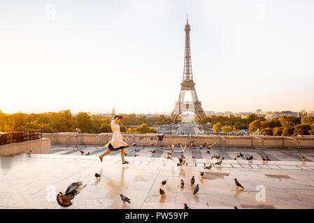 La donna in esecuzione sulla famosa piazza di disperdere i piccioni con una splendida vista sulla Torre Eiffel al mattino presto a Parigi Foto Stock