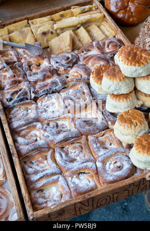 La pasticceria in vassoi di legno su un panificio stallo a Stow on the Wold farmers market. Stow on the Wold, Gloucestershire, Inghilterra Foto Stock