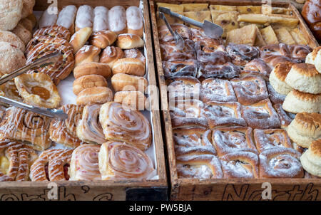 La pasticceria in vassoi di legno su un panificio stallo a Stow on the Wold farmers market. Stow on the Wold, Gloucestershire, Inghilterra Foto Stock