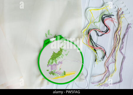 Cerchio da ricamo con tessuto bianco, colorato di fili di cucitura e vari pulsanti di cucitura. Vista da sopra. Foto Stock
