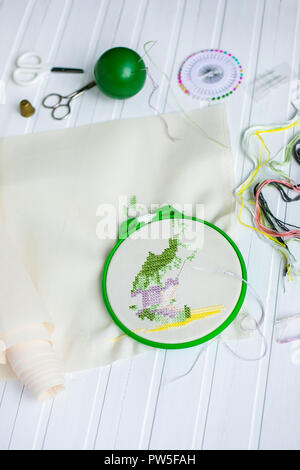 Cerchio da ricamo con tessuto bianco, colorato di fili di cucitura e vari pulsanti di cucitura. Vista da sopra. Foto Stock