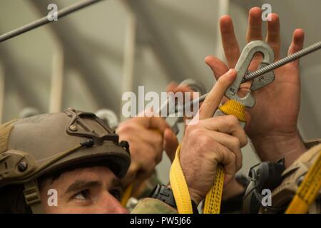 Un berretto verde assegnato al primo battaglione, decimo delle forze speciali Gruppo (airborne), attacca il gancio a scatto del suo universale static line per l'ancoraggio del cavo di linea di un C-130 Hercules mock-up durante il pre-formazione di salto nei pressi di Stoccarda, Germania, Sett. 20th, 2017. La formazione è una parte necessaria del airborne timeline e assicura che tutti i ponticelli hanno una piena comprensione delle procedure durante il salto da un aereo. Operazioni speciali i soldati devono passare almeno quattro volte l'anno per mantenere la competenza in operazioni aviotrasportate. Foto Stock