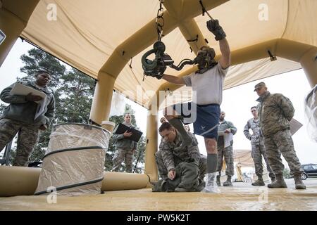 Stati Uniti Air Force Master Sgt. Michael Doane, 436th Training Squadron equipaggi di volo istruttore di apparecchiature da Dyess Air Force Base in Texas, rimuove oltre gli indumenti da U.S. Air Force Senior Master Sgt. Bryan McCoy, Aberdeen Proving Ground Air Force per la gestione del ciclo di vita del centro sovrintendente AFE, durante la contaminazione di equipaggi corso di mitigazione su Ramstein Air Base, Germania, Sett. 19, 2017. Doane ha dimostrato come rimuovere correttamente il indumenti esterni delle apparecchiature di volo come parte del processo di decontaminazione. Foto Stock