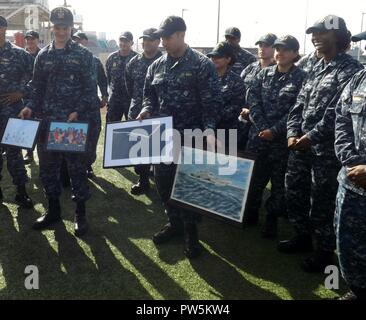 SAN DIEGO (22 settembre 2017) USS Fort Worth (LCS 3) marinai tenere premuto Illustrazione da cittadini di Fort Worth, Texas, date alla nave durante uno scambio del comando cerimonia. L'evento ha segnato anche la nave in cinque anni di anniversario di messa in servizio. Fort Worth è una libertà-variante Littoral Combat Ship ed è progettato per essere veloce e agile, progetto poco profonde e mission-focalizzato con la capacità di operare in marine e oceano aperto. Foto Stock