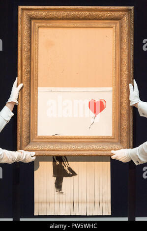 Londra, Regno Unito. Xii oct, 2018. Sotheby's membri dello staff presente Banksy 'l'amore è in bin in London, Gran Bretagna il 12 ottobre 2018. Originariamente intitolato 'Ragazza con palloncino', il British artista di strada Banksy ha fatto la sua pittura si autodistrugge su 5 Ottobre momenti dopo che esso è stato messo all'asta per i 1.042 milioni di sterline inglesi (1,37 milioni di dollari) da Sotheby's a Londra. Credito: Ray codolo/Xinhua/Alamy Live News Foto Stock