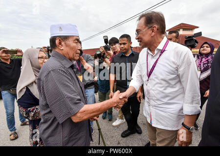 (181013) -- Port Dickson, Ottobre 13, 2018 (Xinhua) -- Malaysia dell ex vice primo ministro Anwar Ibrahim (R) stringe la mano con un elettore in corrispondenza di una stazione di polling durante il parlamentare di elezione in Port Dickson, Malaysia, 13 ottobre, 2018. La Malaysia ha ex vice primo ministro Anwar Ibrahim è previsto per essere votato torna al Parlamento europeo a seguito di elezione di sabato. Gli elettori in Port Dickson, una città costiera e una attrazione turistica, sono attesi per eleggere il 71-anno-vecchio Anwar come membro della Camera Bassa del parlamento, complemento alla sentenza Pakatan Harapan sorprendente vittoria in Ma Foto Stock