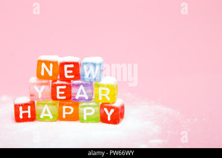 Parole felice anno nuovo fatto di lettere colorate blocchi sul bianco della neve e sfondo rosa. Appartamento laico, vista dall'alto - vacanze inverno, Natale e Anno Nuovo Foto Stock