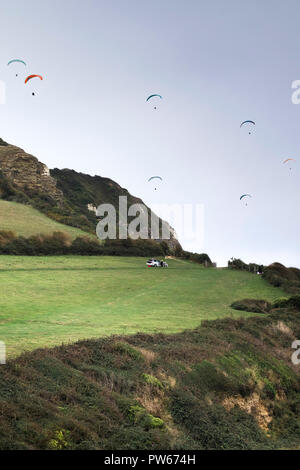 I parapendii sorvolano Hooken Cliff Branscombe nel Devon. Foto Stock