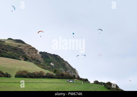 I parapendii sorvolano Hooken Cliff Branscombe nel Devon. Foto Stock