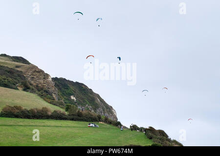 I parapendii sorvolano Hooken Cliff Branscombe nel Devon. Foto Stock