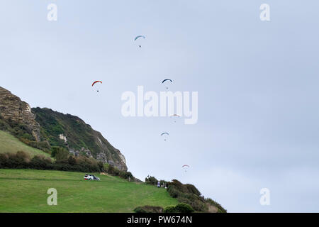 I parapendii sorvolano Hooken Cliff Branscombe nel Devon. Foto Stock