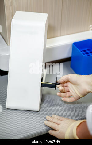 Lo specialista dei luoghi di laboratorio i campioni in uno speciale apparecchio per studiare la composizione Foto Stock