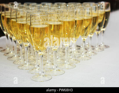 Bicchieri riempiti con vino spumante sul tavolo bianco Foto Stock