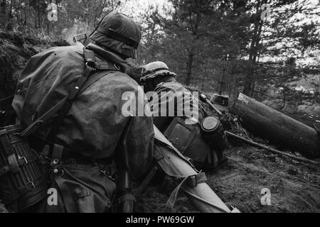 Unidentified Re-enactors vestito come il tedesco della Wehrmacht soldati di fanteria nella guerra mondiale II seduta nascosta con il tedesco hand-held Anti-serbatoio Lanciagranate Foto Stock