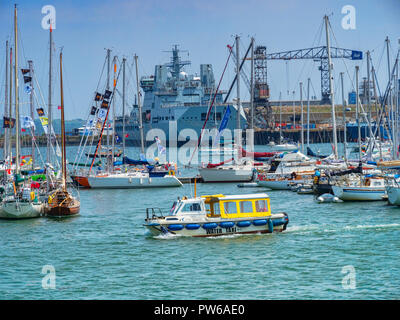 12 Giugno 2018: Falmouth, Cornwall, Regno Unito - Taxi acquatico attraversando Falmouth Harbour, con uno sfondo di barche e di una nave da guerra nel dock. Foto Stock