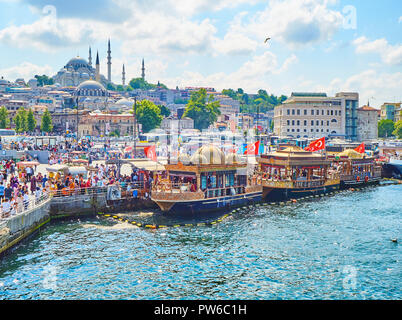 Istanbul, Turchia - 11 luglio, 2018. Il sandwich di pesce barche ormeggiate nel molo Eminonu in corrispondenza della bocca del Golden Horn Baia del Bosforo e il quartiere Eminonu Foto Stock