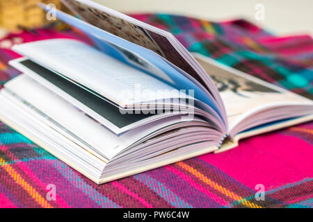 Coperta di tartan libro aperto su un tavolo giardino all'aperto, mock up, flatlay, timeout concetto, hygge, lo stile di vita facile vivere, vita migliore, rilassante atmosfera rilassata Foto Stock