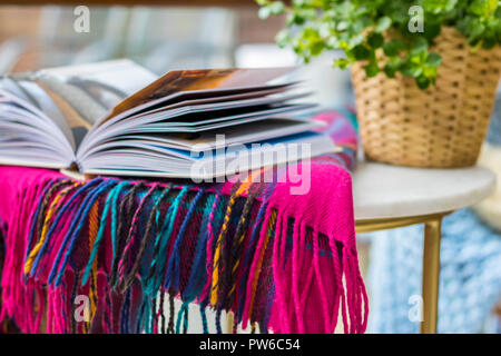 Coperta di tartan libro aperto su un tavolo giardino all'aperto mock up flatlay, timeout concetto, hygge, lo stile di vita facile vivere, miglior vita rilassato rilassante sfocato Foto Stock