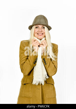 Fiducioso donna sorridente mentre tiene sciarpa fino attorno al collo per mantenere in caldo Foto Stock
