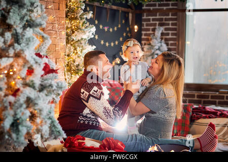 La famiglia felice con un bambino in una sala di Natale. Foto Stock