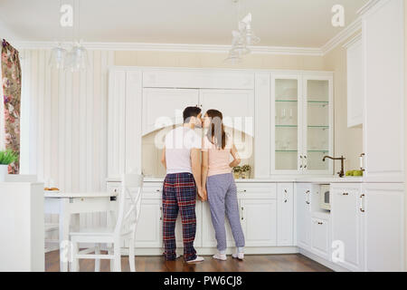 Vista posteriore di una giovane coppia in pigiama stand in cucina. Foto Stock