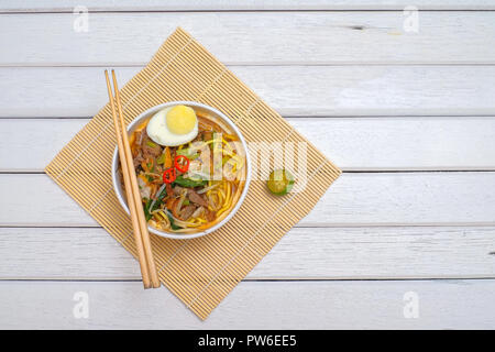 Il malese Mee Rebus nella ciotola con bacchette sul tavolo bianco questo piatto è fatta di tagliatelle ,,vegetale uova con un aroma di . Foto Stock