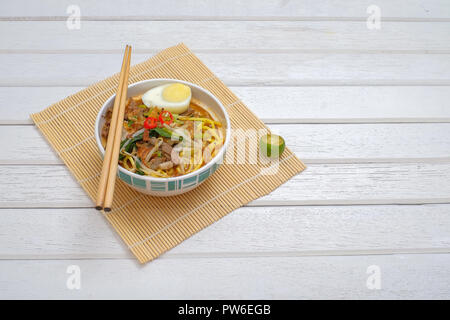 Il malese Mee Rebus nella ciotola con bacchette sul tavolo bianco questo piatto è fatta di tagliatelle ,,vegetale uova con un aroma di . Foto Stock