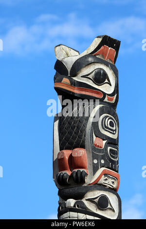 Native American bird motif totem pole con sfondo rosso, Foto Stock