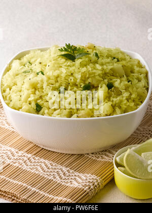 BATATA POHA realizzato da riso soffiato fiocchi di patate e cipolle. servita con calce e peperoncini verdi Foto Stock