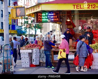 Gli acquirenti asiatici al di fuori del vegetale, il mercato della frutta su un angolo di Mott Street a Chinatown, New York, NY, STATI UNITI D'AMERICA. Foto Stock