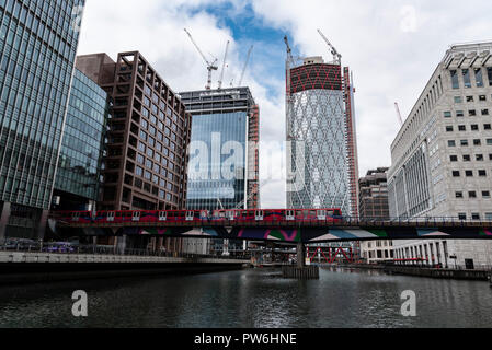 Treni DLR passando da edifici in costruzione al Canary Wharf Foto Stock