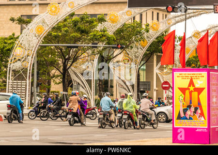 Motociclista in passato una delle molte comunità di Governo segni sulle strade di Da Nang Vietnam Foto Stock