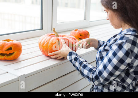 Zucca di Halloween processo di taglio. Giovane donna rendendo jack-o-lantern. Foto Stock