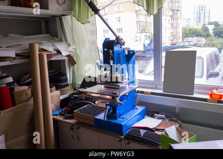 Premere la macchina in officina per fare il logo in rilievo e lettere sul manufatto in pelle che riscalda il cliché e spreme l'immagine desiderata su t Foto Stock