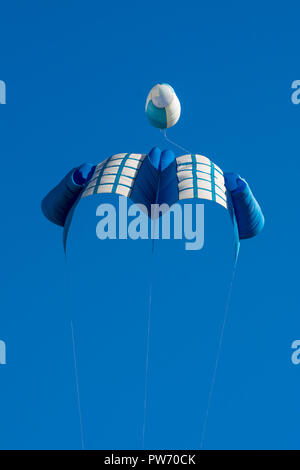 Un brillante, blu-bianco singolo kite in un cielo blu chiaro Foto Stock