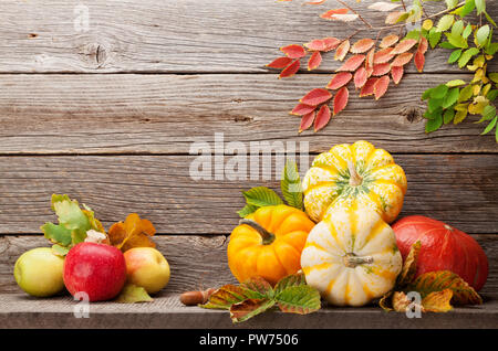 Autunno con zucche, mele, pere e foglie colorate nella parte anteriore della parete in legno. Con spazio per il testo Foto Stock