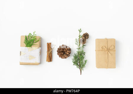 Confezioni regalo avvolto in carta artigianale legata con lo spago nastro di tessuto pigne ginepro cannella solido su sfondo bianco. Nuovo anno presenta holiday prepa Foto Stock