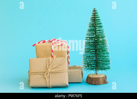 Pila di confezioni regalo avvolto in carta artigianale legata con lo spago rosso nastro bianco albero di Natale di menta su sfondo blu. Anno nuovo corporate presenta shoppin Foto Stock