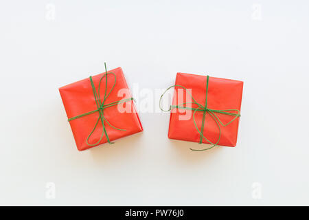 Due confezioni regalo avvolto in carta rossa legate con nastro verde. Sfondo bianco. Holiday nuovi anni Natale regali aziendali vendita shopping. Divieto di poster Foto Stock