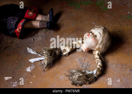 Kuldiga, Lettonia. 19 Agosto, 2014. La rottura di una bambola si trova gettato sul pavimento di una casa abbandonata in Kuldiga, Lettonia. Foto Stock