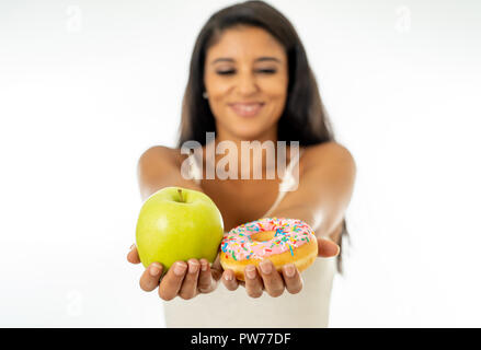 Bella felice giovane donna azienda apple e ciambella in sano cibo malsano, detox mangiare, calorie e il concetto di dieta. Foto Stock