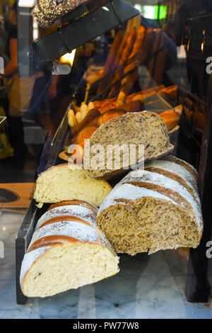 La finestra del display di un panificio e pasticceria. Assortimento di diversi tipi di pane appena sfornato il pane artigianale della segala tutta la crusca di frumento pani. Autentico urban Foto Stock