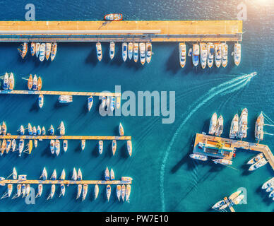 Vista aerea di incredibili imbarcazioni al tramonto. Paesaggio minimalista con barche e mare di Marina Bay. Vista dall'alto da fuco del porticciolo di yacht, un motoscafo Foto Stock