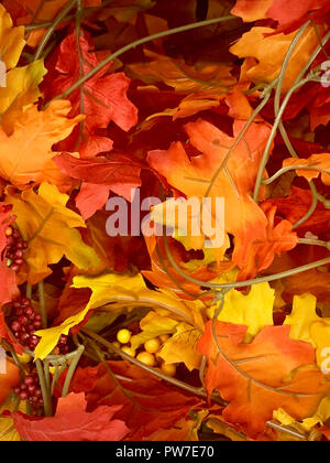 Un composito di foglie prevalentemente arancioni, rosse e gialle di una vite verde in orientamento verticale. Foto Stock