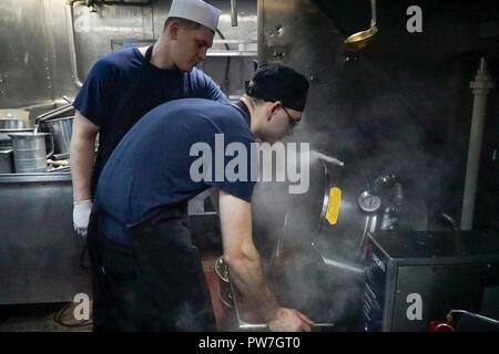 Oceano atlantico (sett. 21, 2017) - specialista culinaria marinaio Dominic Lauber, da Buffalo, New York, anteriore, prepara il cibo per l'equipaggio di Arleigh Burke-class guidato-missile destroyer USS James E. Williams (DDG 95), Sett. 21, 2017. James E. Williams, home-ported a Norfolk, è su una distribuzione di routine per gli Stati Uniti Sesta flotta area di operazioni a sostegno degli Stati Uniti per gli interessi di sicurezza nazionali in Europa. Foto Stock