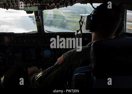 Stati Uniti Air Force Capt. Kyle Brackett, XXI Airlift Squadron C-17 istruttore pilota, piloti un C-17 Globemaster III aeromobile assegnati per il XXI Airlift Squadron, prima di atterrare a U.S. La stazione navale di Guantanamo Bay a Cuba, Sett. 23, 2017. Il C-17 aveva appena consegnato 105.000 libbre e 18 pallet di acqua e MREs a St. Croix dopo l'isola aveva subito danni dall uragano Maria. Foto Stock